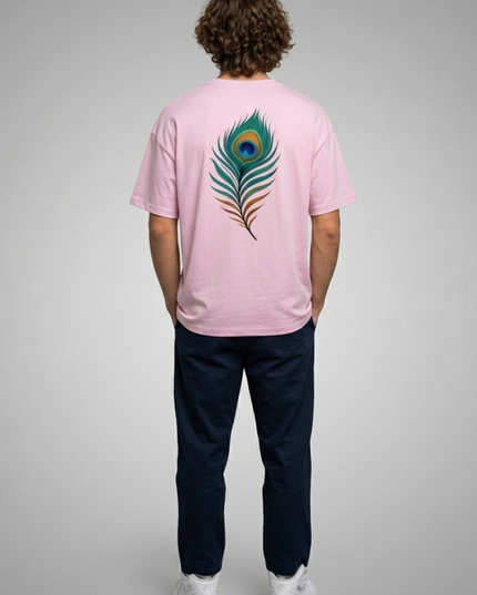 Person wearing a pink t-shirt with a peacock feather design on the back, standing against a gray background.