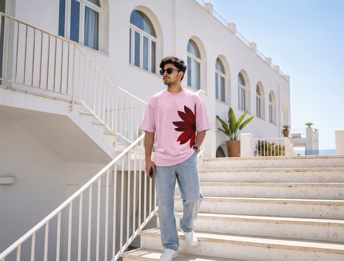 Man in a pink t-shirt with a red flower design walking up steps in front of a white building.